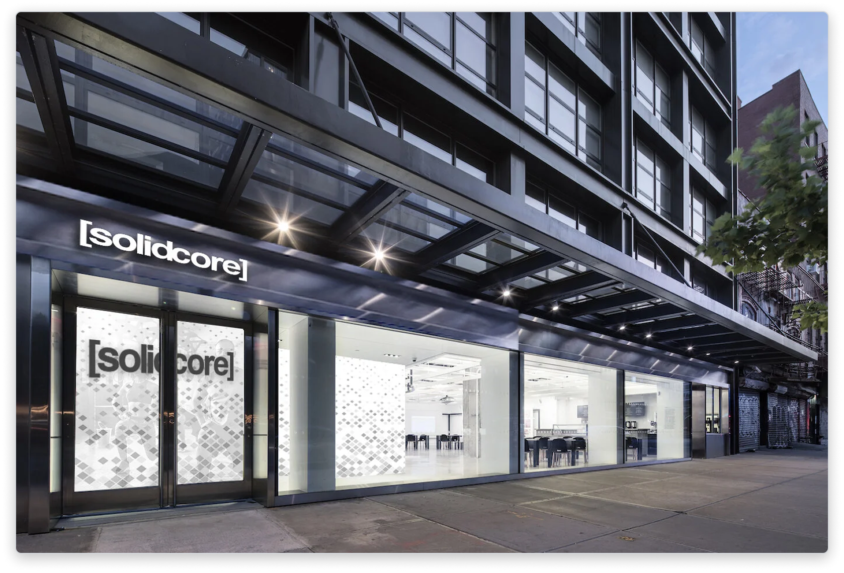 Composite placing a [solidcore] storefront into an existing retail frontage at night